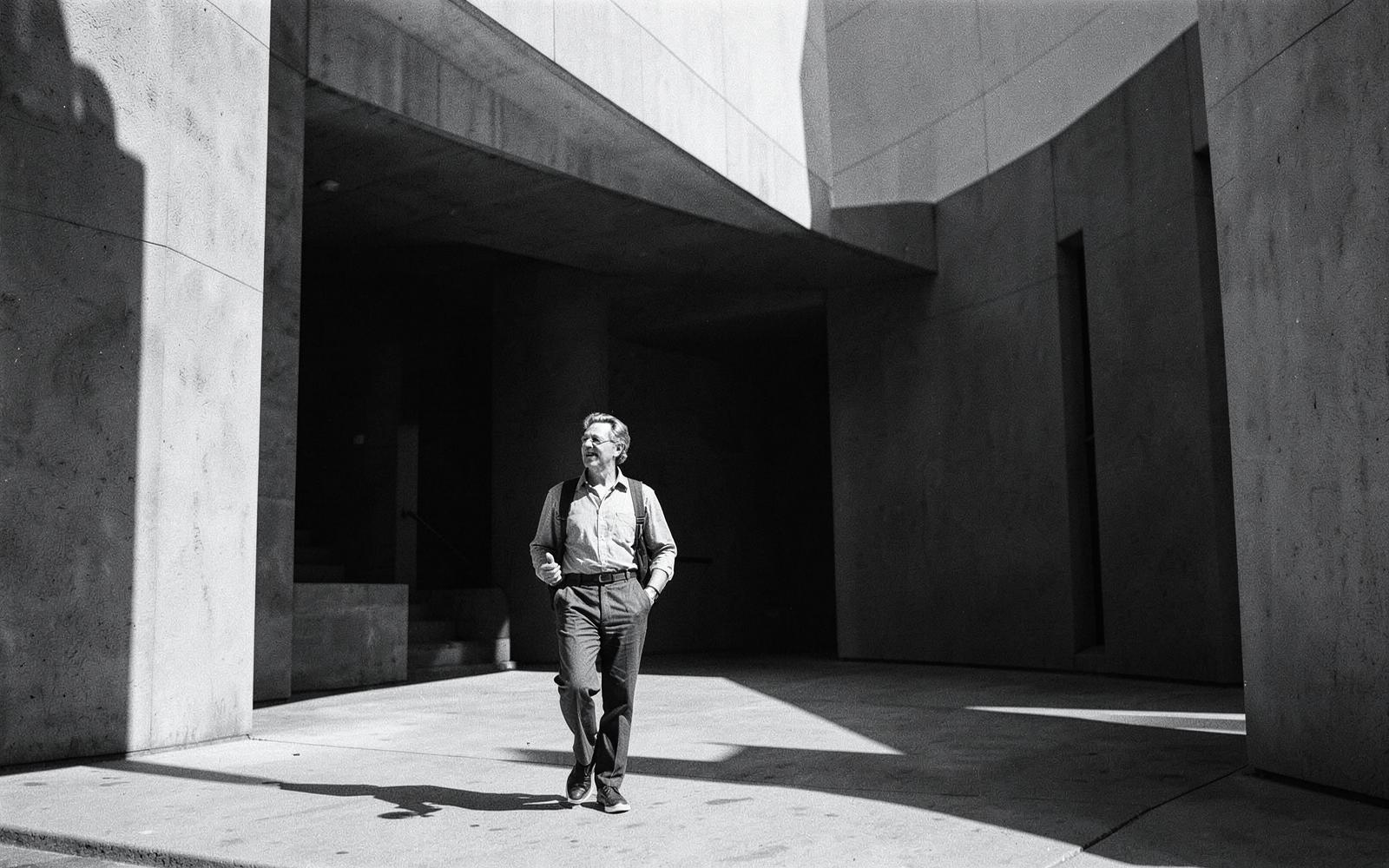 A person crossing a modernist space of light and shadow
